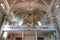 Interior of a catholic church in South Tyrol with numerous ornate columns, a golden pipe organ