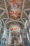 Interior of a catholic church in South Tyrol with numerous ornate columns, a golden pipe organ