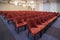 Interior of a conference room. Beautifully arranged and lined red chairs with blue carpet and lights in the background