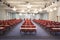 Interior of a conference room. Beautifully arranged and lined red chairs with blue carpet and lights in the background