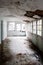 Interior corridor of an abandoned hospital with collapsing roof and broken windows