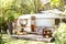 Interior cozy yard campsite with fall flowers potted and pumpkins. Wooden RV house porch with garden furniture.