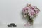 Interior decoration, pink rhododendron bouquet in glass vase, three black stones, copy space