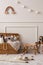 Interior design of kids room interior with wicker basket, plush animal toys, poster, wooden blockers, ladder, white stool, beige