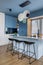 Interior design of kitchen interior with marble kitchen island, blue wall, black chokers, bowl with fruits, big window, cup,