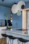 Interior design of kitchen interior with marble kitchen island, blue wall, black chokers, bowl with fruits, big window, cup,