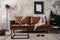 Interior design of loft industrial apartment with mock up poster frame, modern brown sofa, square coffee table, black commode and