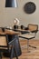 Interior design of modern dining room space with stylish chairs, wooden table, black pedant lamp, decoration, ceramic vessel.