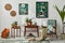 Interior design of retro living room with stylish vintage armchair, shelf, house plants, decoration and two mock up poster frames.