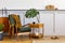 Interior design of stylish living room with vintage green armchair, wooden coffee table, furniture, grey wall, shelf, carpet.