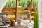 Interior design of summer gazebo by the lake with stylish rattan armchair, coffee table, sofa, pillows, plaid, elegant.