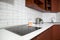 Interior of domestic kitchen with cooktop electric touch stove and long white tabletop with sink