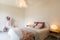 Interior of elegant double bedroom. Colorful blankets and pillows and a clothes drying rack in the background. Nobody inside