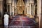 Interior of the Great Mosque of Sousse with chandeliers and prayer rugs with a devout Muslim to the side