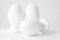 Interior home or church decor of three white ceramic eggs on stands or in egg-cups on white blurred background. Easter religious C
