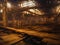 The interior of a large derelict deserted old factory with light from the broken windows reflected on the wooden floor.