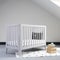 Interior of light baby room with a modern crib and woven wicker boxes for clothes or accessories