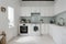 Interior of light kitchen with washing machine, oven and white counters