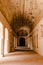 Interior of the long hallway with an archway entrance in Orchha Fort in India