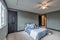 Interior master bedroom with large blue bed and ceiling fan dark wood closet door