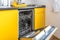 Interior of the modern kitchen with opened Dishwasher in loft flat apartment in minimalistic style with yellow color