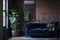 The interior of a modern living room with a dark blue sofa next to a brick wall on which a horizontal poster hangs, in the