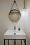 Interior of modern style bathroom in refurbished apartment. White sink with black faucet and round mirror frame, lighted