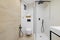 Interior of modern style bathroom in white and beige colors in refurbished apartment. Shower zone and toilet, with black