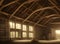 The interior of an old wooden rural barn with atmospheric sunlight coming through windows and an open door.