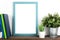 Interior poster mock up with vertical wooden frame, books and house plants on white wall background