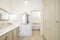 Interior of retro or classic style bathroom decorated in beige color with bath zone, big wardrobe, two sinks and vintage