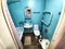 The interior of a small, modest bathroom with a bath and a toilet. Green walls, curtains with a red dot. The concept of