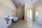 Interior of spacious light hospital or kindergarten bathroom with white bathtub, sink, air ventilation duct and tiled floor and