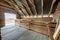 Interior of unfinished brick house with concrete floor, bare walls ready for plastering and wooden roofing frame attic under