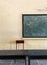 An interior view of a classroom with blackboard and benches.