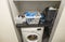 Interior view of laundry cabinet.  Basket with clean clothes and iron over washing machine