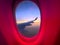 Interior window of airplane from where you can see the commercial wide-body wing ascending to cruising altitude.