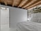 interiors of a bedroom with stone walls and wooden beamed ceiling the floor is made of gray resin