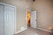 Interiors of the entrance of a room with white doors, beige walls and a carpet