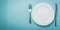 Intermittent fastin concept - empty plate on blue background