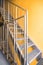 Internal metal fire escapes of a modern building, modern metal ladder. Fire escape in a modern house with yellow walls