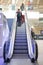 Internal view of customers on escalators inside a modern shopping centre mall