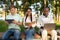 International college classmates preparing for lectures outdoors, sitting in university campus with books and devices