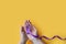 International Epilepsy Day. Adult hands holding purple ribbon on yellow background. Alzheimer`s disease, Pancreatic cancer,