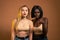 International female`s couple in beige bra looking at camera with frightened expression, shocked and terrified, african