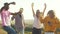 International friends dance in nature holding cocktail in their hands against the sky, front view. Four people dancing