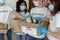 International group of young volunteers sorting donated food in boxes, working in charity donation center, closeup