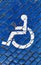 International handicapped symbol painted in bright blue on a paving street parking space.