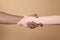 International relationships. People holding hands on light brown background, closeup