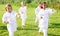 International team of tweens exercising taekwondo techniques on green lawn